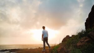 Personne seule sur falaise au coucher du soleil, crise existentielle et quete de sens