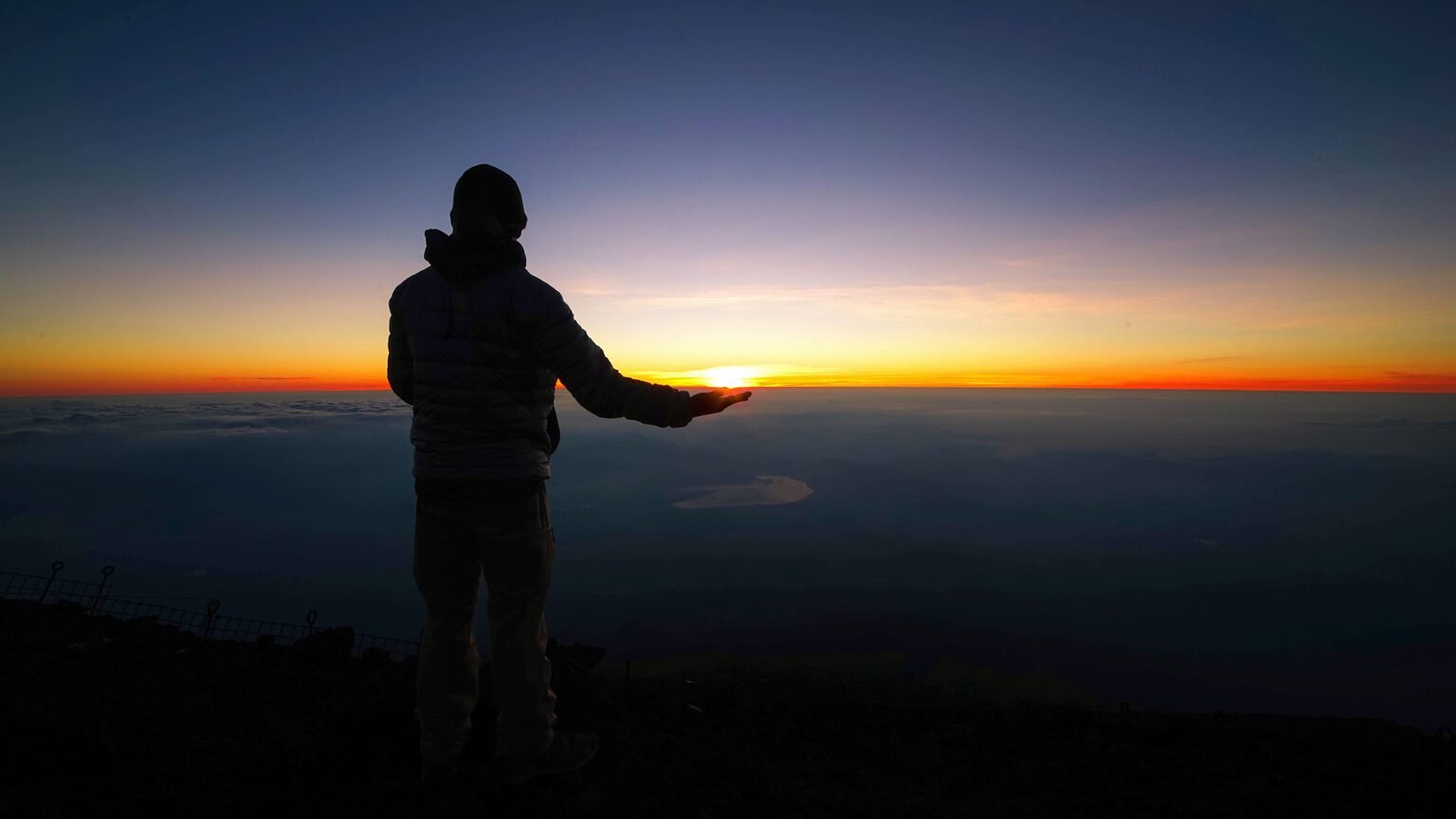 Personne debout au sommet d'une montagne au lever du jour