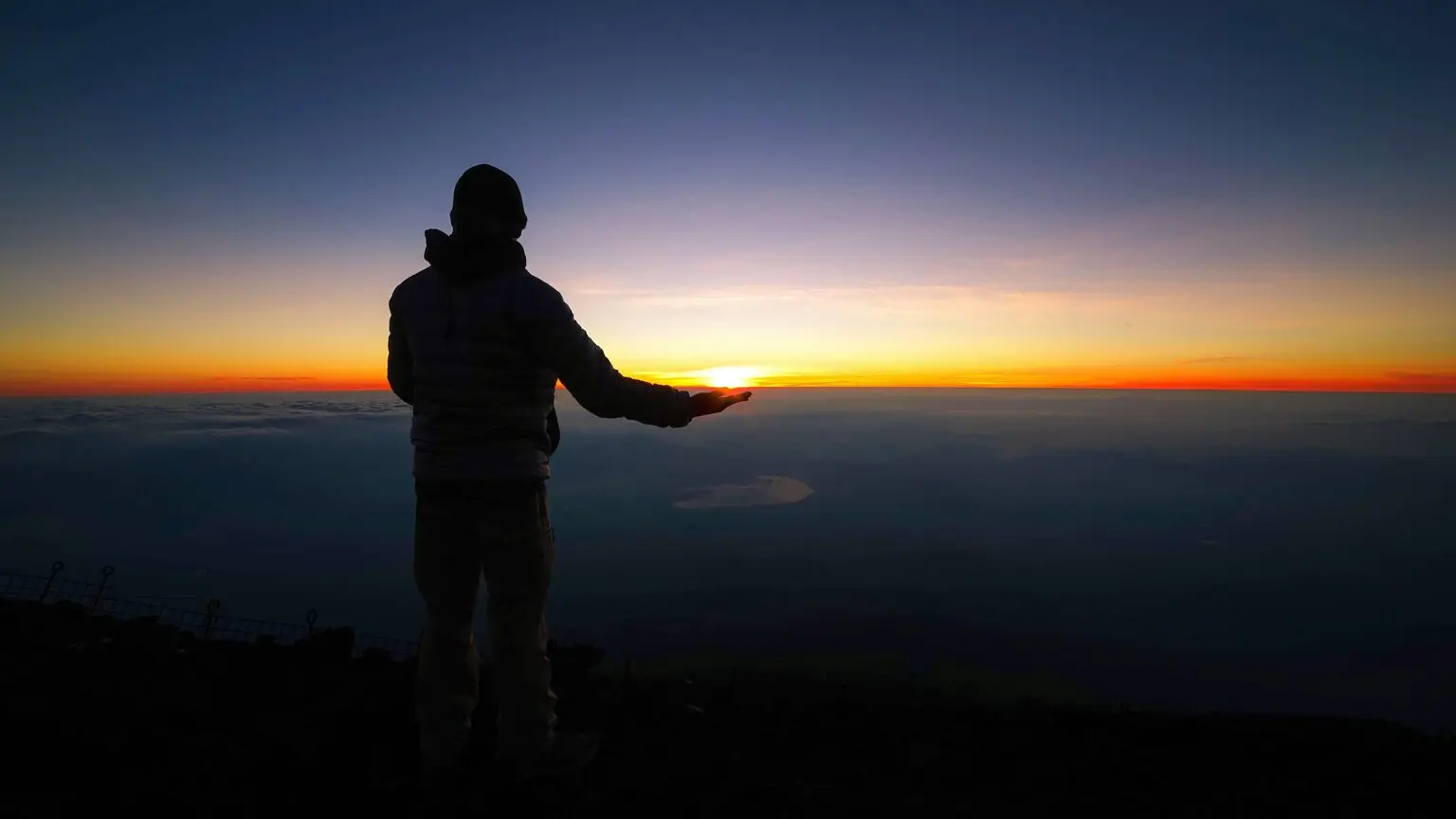 Personne debout au sommet d'une montagne au lever du jour
